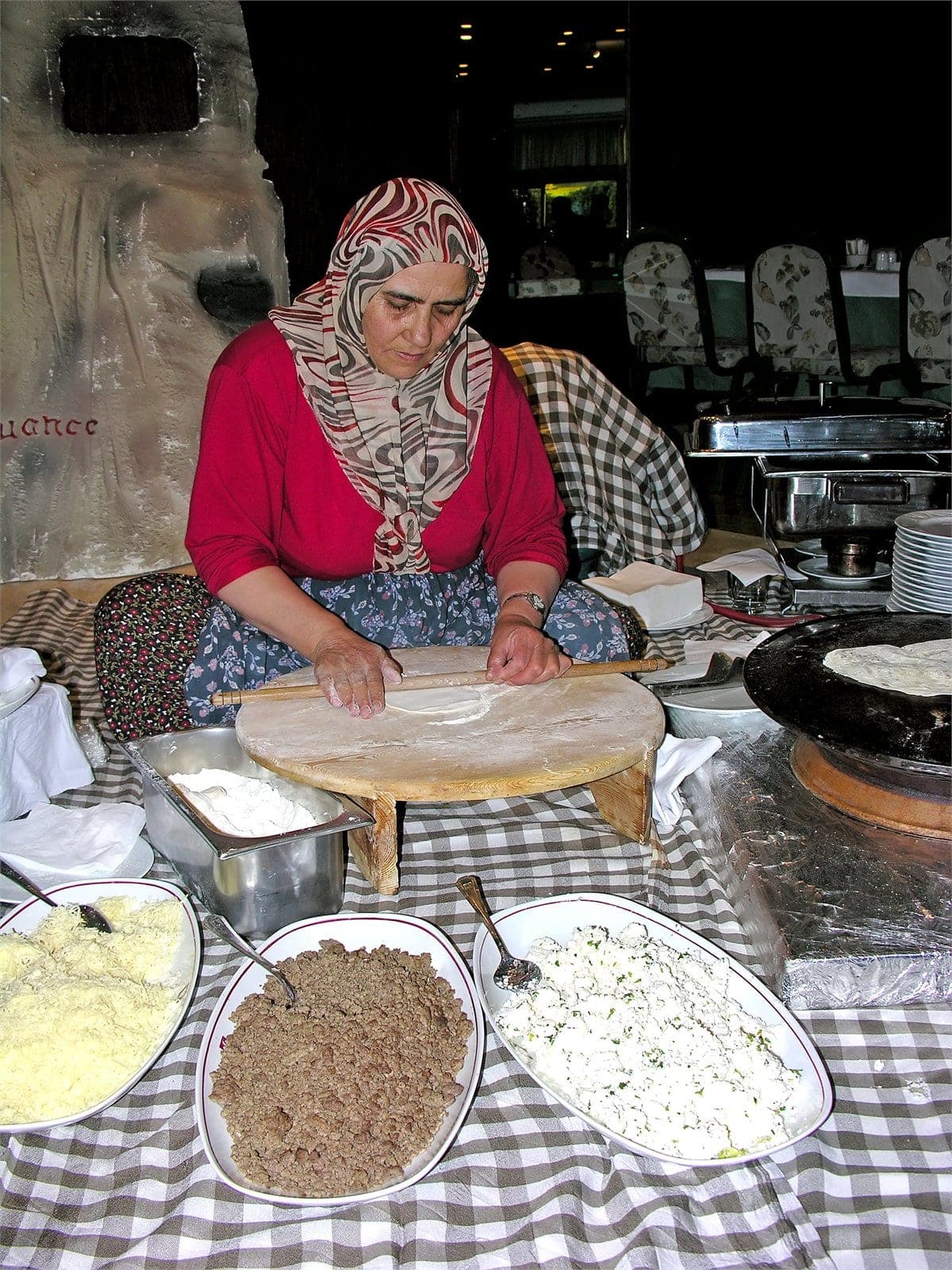A Cappadocian village cook rolling gözleme dough by hand on a low wooden table