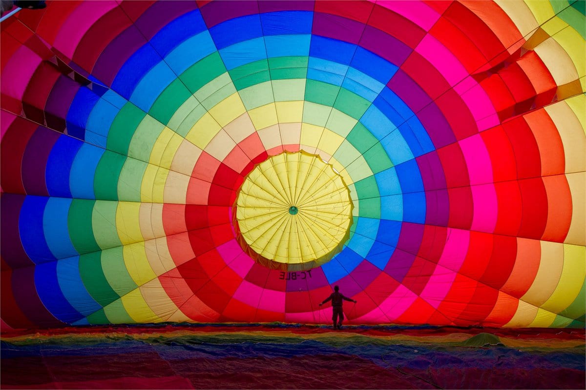 The coloured canopy of a hot air balloon glowing during pre-dawn inflation