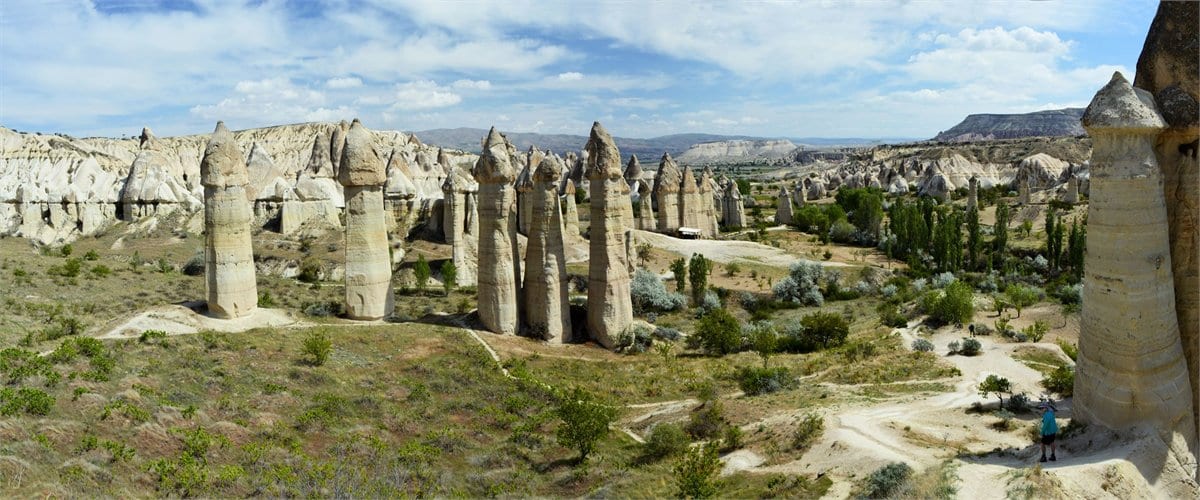 Sun-lit fairy chimneys and a dry valley floor in Cappadocia on a clear August afternoon