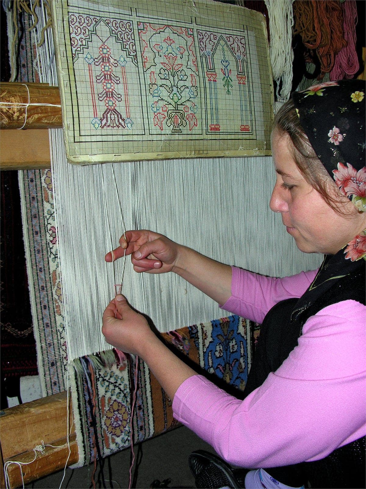 A weaver’s hands knotting wool on a traditional carpet loom in Cappadocia
