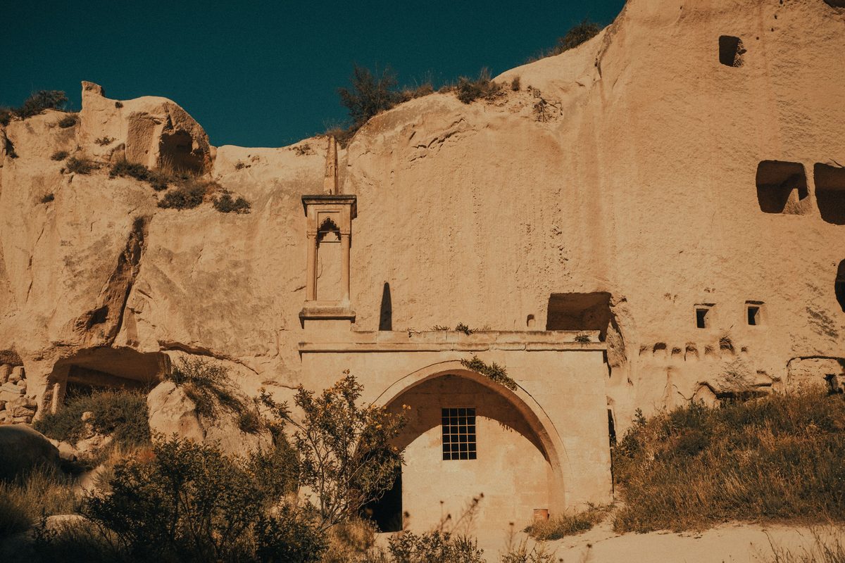 The rock-cut mosque at Zelve, with its arched stone entrance and small minaret set against the cliff face